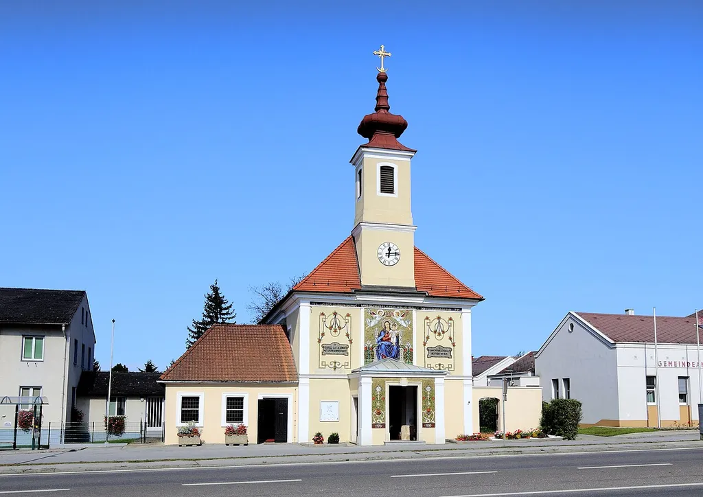 Südansicht der Pfarr- und Wallfahrtskirche Unsere Liebe Frau in Maria Ellend, ein Ortsteil der niederösterreichischen Gemeinde Haslau-Maria Ellend. Der schlichte Bau mit einem Fassadenturm wurde 1770 errichtet. Im Zuge einer Innen- und Außenrenovierung sowie einem teilweise Umbau 1910 wurde auch das Fassadenmosaik angebracht.