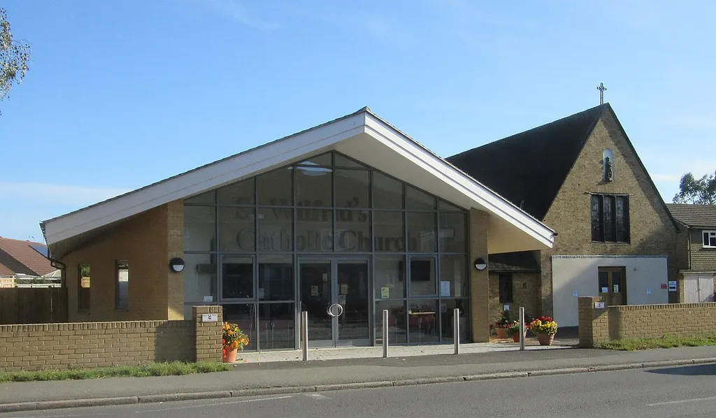 The current (left) and former (right) St Wilfrid's Roman Catholic churches, South Road, Hailsham, East Sussex, England. The new church opened in October 2015 and was built on spare land between its 1955 predecessor (the smaller building to the right, with a steeply pitched roof) and the original church of 1922 (out of shot to the left).