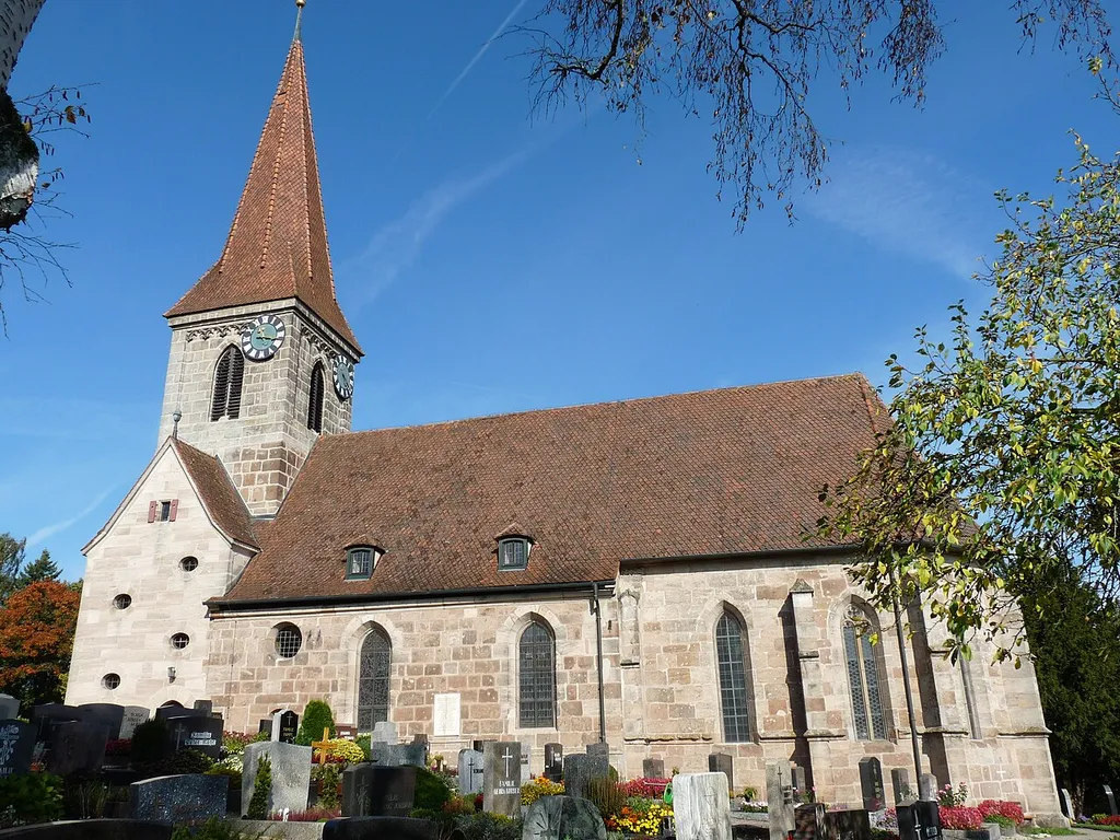 Die Evang.-lutherische Walburgskirche mit dem Friedhof von Süden her fotografiert. Sie thront am hohen Kirchberg in Großhabersdorf und an klaren Tagen kann man von der Anhöhe sogar die Türme der fränkischen Großstadt Nürnberg sehen. "Nach Helmut Mahr ist sie frühestens um 900 spätestens 1057 - 1075 gebaut worden. Da die Kirche in Großhabersdorf der heiligen Walburga gewidmet war, deren Heiligsprechung um 870 - 879 erfolgte, kann das ihr geweihte Gotteshaus erst nachher entstanden sein. Die Kirche ist ein gotisches Bauwerk mit Westturm, Langhaus und Chor (Entnommen aus Großhabersdorf - Eine Gemeinde im Wandel der Geschichte von Michael Kroner)" Die Kirche ist schlicht im Inneren; ein kleiner Barockaltar mit zwei gedrehten Säulen befindet sich vor der Orgelempore. Bunte Glasfenster in kräftigen Farben, Meisterwerke des Nürnberger Kunstkreises aus dem 14. Jahrhundert, leuchten zu beiden Seiten der Orgel. Seit 1516 zeigt die Großhabersdorfer Turmuhr die Stunden an.