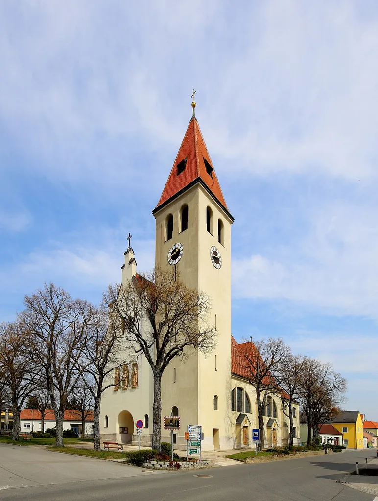 Südwestansicht der katholischen Pfarrkirche Maria Geburt in der niederösterreichischen Marktgemeinde Enzersfeld im Weinviertel. Die Kirche wurde von 1908 bis 1909 im sezessionistischen, romantisierenden Stil errichtet.