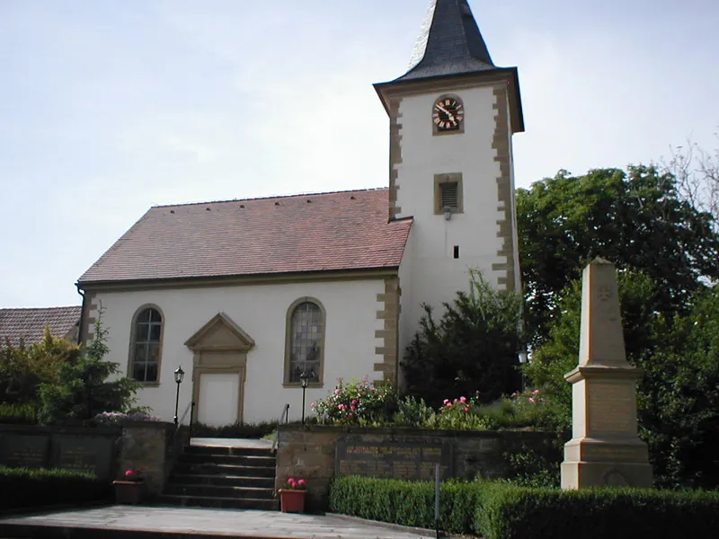 Evangelische Kirche in Kälbertshausen. Davor das Kriegerdenkmal des Ortes.