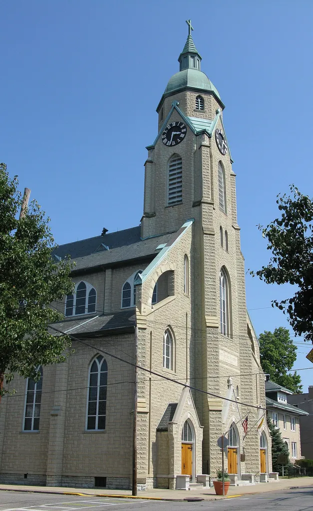 Sacred Heart Church is a Catholic parish church in Bellevue, Kentucky. It's corner stone reads "Sept 25, 1892." The sign in front of it reads, "BELLEVUE LANDMARK - This structure, which resembles the provincial Bavarian churches, was designed by Cincinnati architect Louis Picket. Alters with ogee arches, elaborate niches, finials, architraves, and bar tracery were handcarved in Germany. The triple clerestory windows have stained glass of European narrative type. Murals created by local artists Leon Lippert and Theodore Brasch."