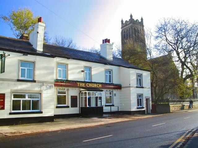 The Church Inn, Chapel Road, Hollins, Greater Manchester, with St Margaret's parish church in the background.