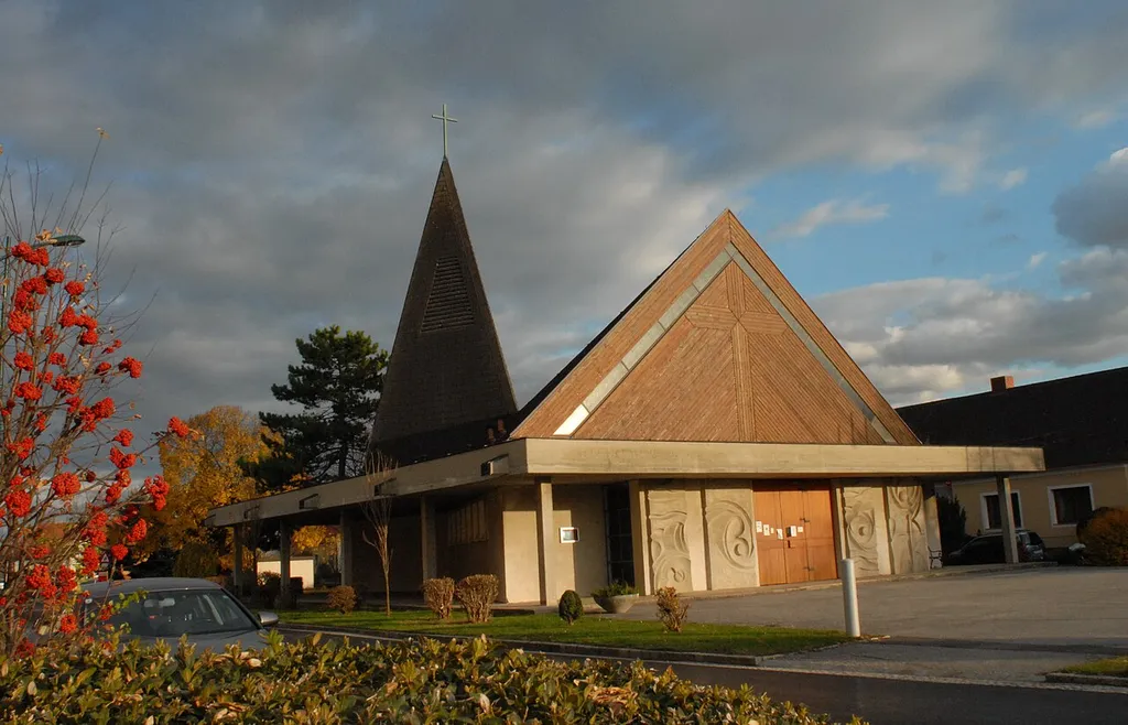 Die dreieckige Form des Grundrisses und der Längsschnittes lässt alle sichtbaren Linien im Altarraum konvergieren und erhöht die Konzentration. Der ebenfalls dreieckige Turm durchdringt das Dach und bildet über dem Altar einen Baldachin, gleichzeitig Blendschutz gegen das von oben auf den Opfertisch niederflutende Licht. Die Kirche steht auf dem schmalen Dorfanger.