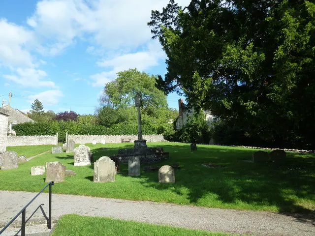 Part of the parish churchyard of St Michael &amp; All Angels, Butcombe, Somerset. In the centre, in the shade of the tree to the right, is a 15th-century churchyard cross.