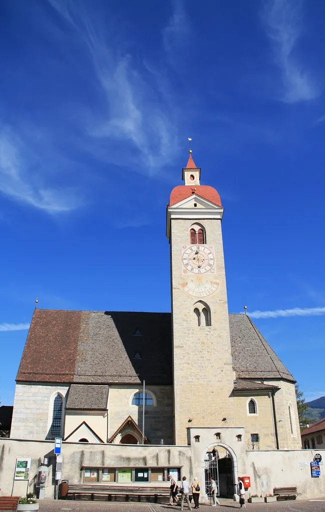 Italy, South Tirol, Natz-Schabs, Schlossergasse, Pfarrkirche Hll. Aposteln Philippus und Jakobus. The first mention of the parish church in Natz dates back to 1157 but the church was consecrated in 1208 by the prince-bishop Konrad von Rodank in honour of Saint Philip and Saint Walpurga. The present church was completed in 1484 in Late Gothic and consecrated once again to the Saints Apostles Philip and James. The bell tower was built in 1400 with granite blocks; in 1635 was damaged by fire and in 1686 was covered with a dome in Baroque style. The high altar is work by Peter Lapper of Natz made in 1855. In the throne of the high altar are the statue of the Madonna, Saint Agnes and Saint Ursula which are Gothc works of 1499 attributed to Michael Parcher; the statues of St. Philip and St. James are by F. X. Renn of Imst made in 1857. The painting of the right lateral altar represent the Baptism of Jesus and the left side altar correspond to the Holy Family, both works are by Michael Lackner of Bruneck. The first organ was installed on May 1st, 1909; the present one has been built by Orgelbau Pirchner of Steinach am Brenner and has 16 registers and 1250 pipes and was inaugurated on May 1st, 1990.