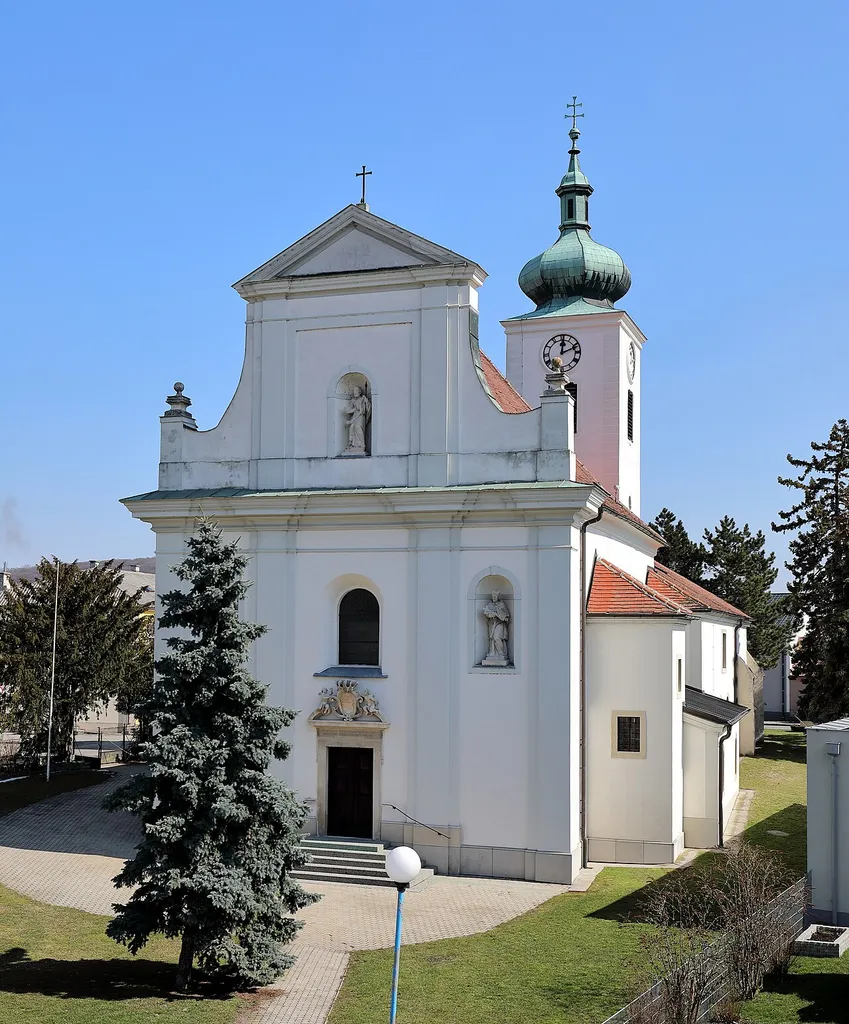 Wwestansicht der röm.-kath. Pfarrkirche hl. Thomas in der niederösterreichischen Marktgemeinde Enzersdorf an der Fischa. Eine romanische Chorturmkirche mit einem barocken Langhaus, das 1714/15 errichtet wurde.