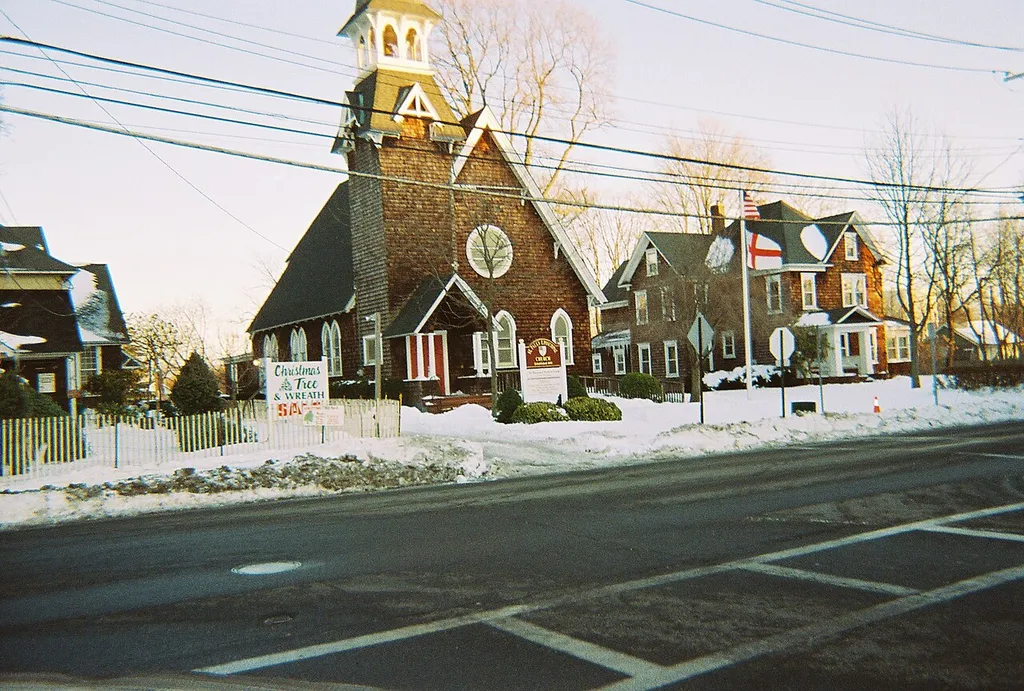 A southeastern view of the historic St. Paul's Episcopal Church Complex in Patchogue, New York. The complex consists of the church in the center, one house on the right, and another on the left. Though the National Register of Historic Places lists the church as being at 31 Rider Avenue, 31 Rider Avenue is actually the address for that house on the right. This picture was taken from the northwest corner of Rider Avenue and Terry Street.