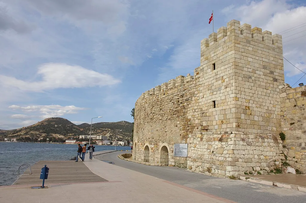 Wikipedia has "The fortification wall around the ancient city of Phocaea was built in 590-580 BC. The walls underwent restoration during the Byzantine Empire era. The castle was a part of the Republic of Genoa in the 13th century, and it was rebuilt by the Genovese. In the 14th century, Ottoman prince Şehzade Halil was kidnapped and retained in the castle. The fortification was restored in 1538 by Ottomans after the city was annexed. The castle stretches over the peninsula." This tower has become under attack for being restored in such a way, it did not fit criteria for a UNESCO heritage site.
