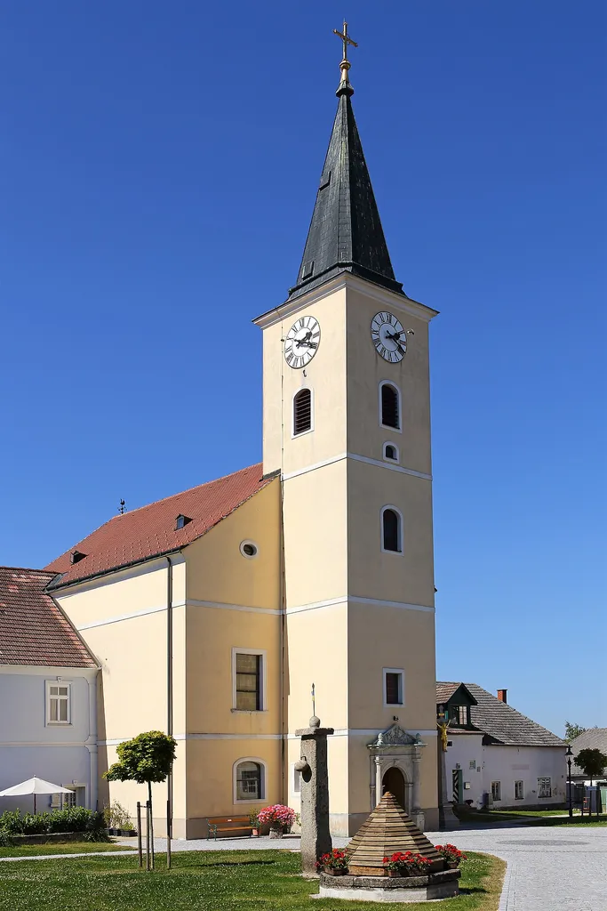 Kath. Pfarrkirche Kreuzerhöhung in Hirschbach. Im Vordergrund: Der ebenfalls unter Denkmalschutz stehende Pranger