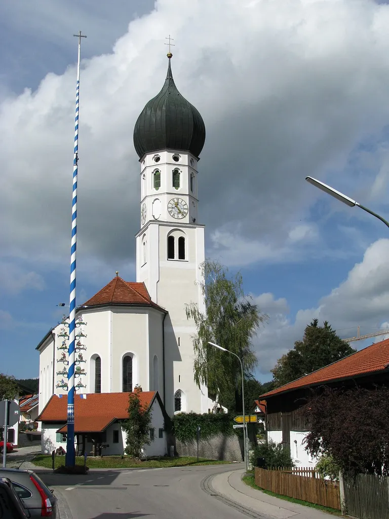 Kath. Filialkirche St. Benedikt, barocker Saalraum mit eingezogenem Polygonalchor und nördlichem Zwiebelturm, von Georg Zellermair, 1631–49, Turmuntergeschoss 1532, Obergeschoss 1659/60 und 1708 erneuert, Umgestaltung 1734; zwischen Maibaum und Kirche die ehemalige Dorfschmiede