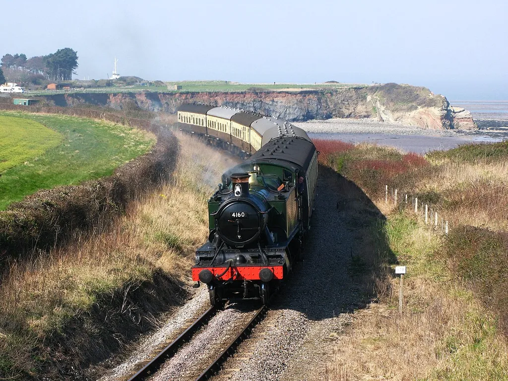 4160, a former Great Western Railway 5101 Class locomotive, heads east along the Somerset coast at Helwell Bay, Watchet, with a train from Minehead to Bishops Lydeard. The bay is part of the Blue Anchor-Lilstock Site of Special Scientific Interest noted for its geological formations, some of which can be seen in the background.