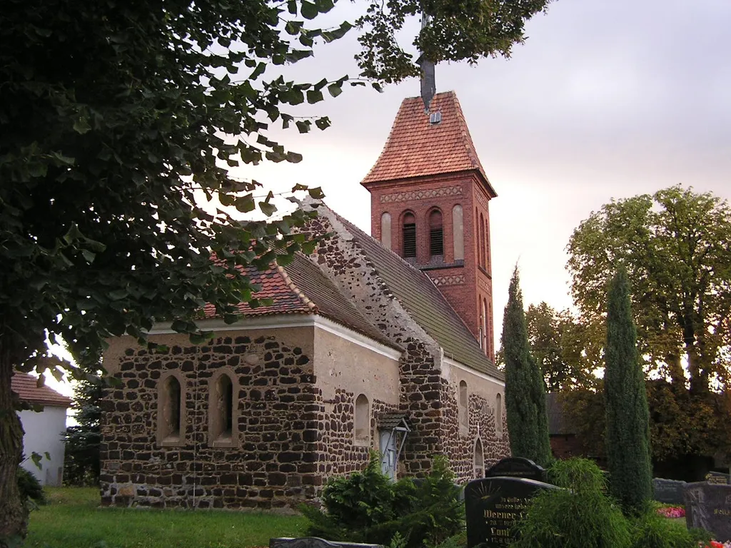 Kirche von Gruhno, Hauptstr. 8 (Landkreis Elbe-Elster). Der denkmalgeschützte Bau aus Raseneisenstein entstand in der 1. Hälfte des 13. Jh. und war ursprünglich mit einem Dachreiter versehen. Der westliche Glockenturm wurde erst 1885/86 errichtet.