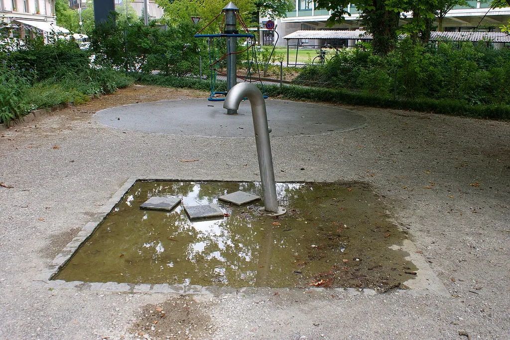 Brunnen Spielplatz Lorraine-Anlage mit Gebäude Gewerbeschule Bern im Hintergrund links.