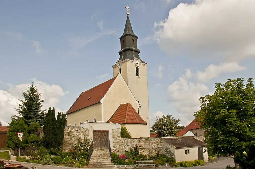 Der ursprünglich romanische Bau wurde im 15. Jahrhundert gotisiert und 1666 barockisiert. Die Kirche ist von einem ehemaligen Friedhof und einer Bruchsteinmauer umgeben.