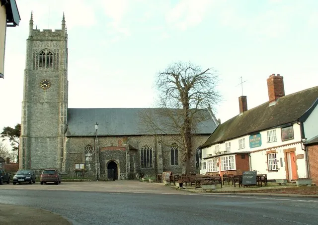 Church of All Saints in Laxfield, Suffolk, England. A Grade I listed medieval church. On the right is the Grade II listed Royal Oak pub.