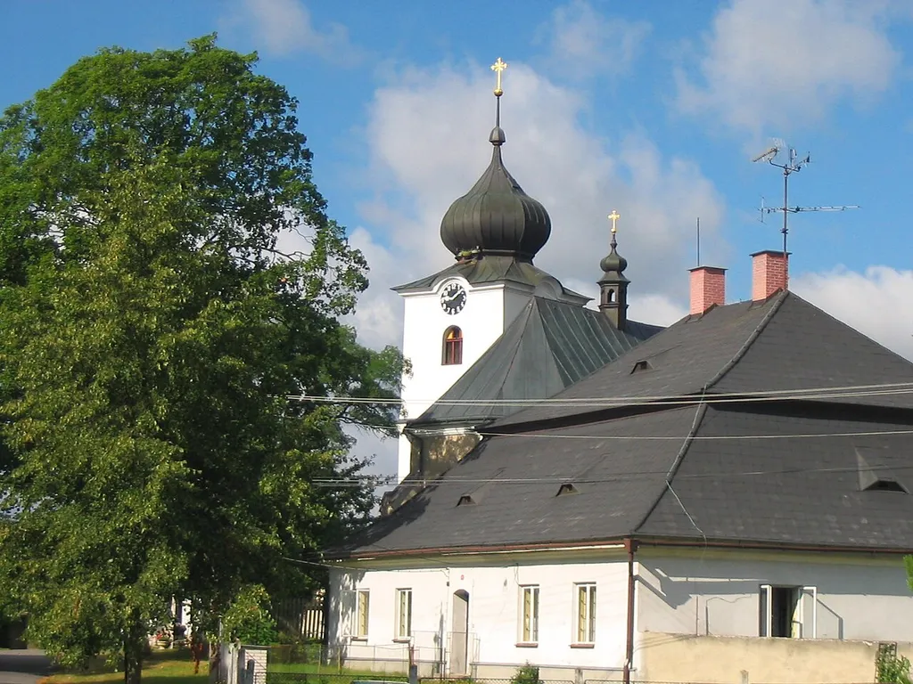 Pohled na kostel Sv. Mikuláše v Nížkově, před kostelem stojí nově opravená fara.
