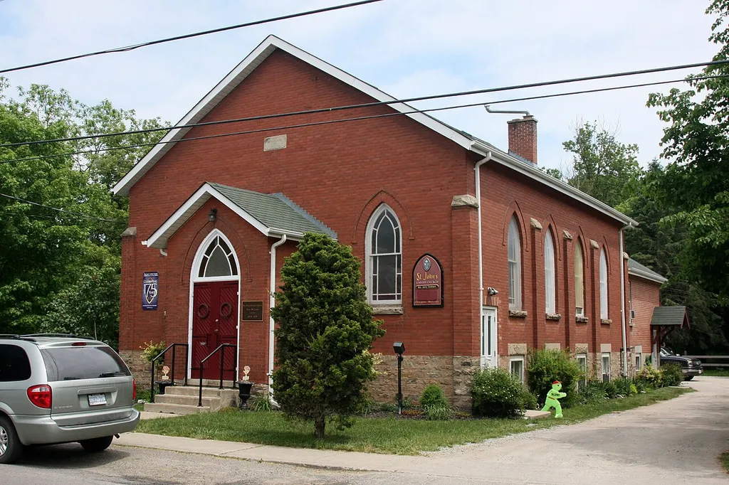 St. John's United Church, 533 Main Street in Glen Williams, Ontario, Canada. Constructed 1840 (bricked over in 1903) • Unique wood frame Methodist church built 1840 and bricked over in 1903 • Has functioned as a church since 1840 • Located in the heart of Glen Williams next to the Credit River One of the first land severences made by Benajah Williams was in July 1840 when he put his shaky signature to the deed which sold to the Methodist Episcopal Trustees its land for a church and burial ground, for five shillings. There is no record of anyone being buried on site since the land is so close to the river, but a wood frame church was built and used for services until 1903. In 1903 the church was renovated and brick walls were added directly overtop of the existing wooden structure. The Williams family, founders of Glen Williams, supported the Methodist Episcopal church, and Charles and Jacob Williams were among the first trustees of the congregation in the Glen. The other trustees were the minister, Morris Kennedy; a yeoman, Henry Grass; and a carpenter and joiner, George Kennedy (who gave his name to the neighbouring village of Georgetown). When the church was bricked over in 1903 (was there a little rivalry with their Anglican neighbours, who were putting up their stone church, St. Alban the Martyr Anglican Church, across the river at the same time?), a stone was cut to indicate that the congregation dated back to 1837. The Methodist Episcopal church became part of the Methodist Church in 1884 (which included the Wesleyans), and this in turn helped to form the United Church of Canada in 1925.