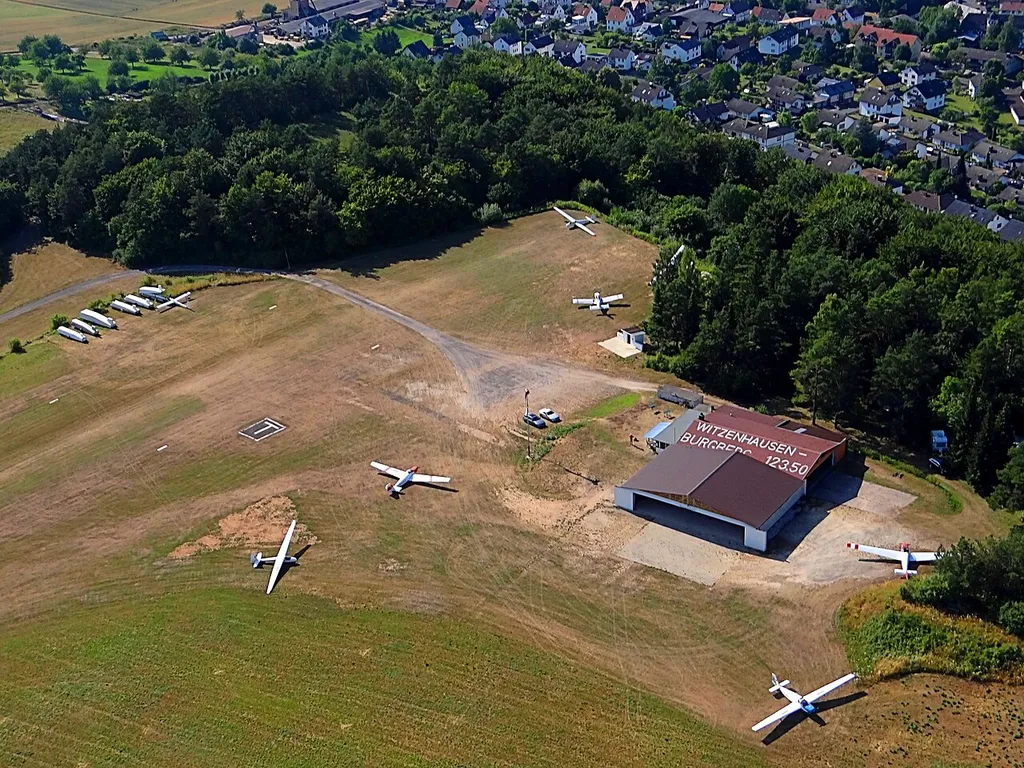 Luftbild vom Flugplatz Witzenhausen auf dem Burgberg. Luftaufnahme aus Süden: links oben bis mittig oben – das Wald- und Hügelgebiet: Lage der ehemaligen Königspfalz Ermschwerd.