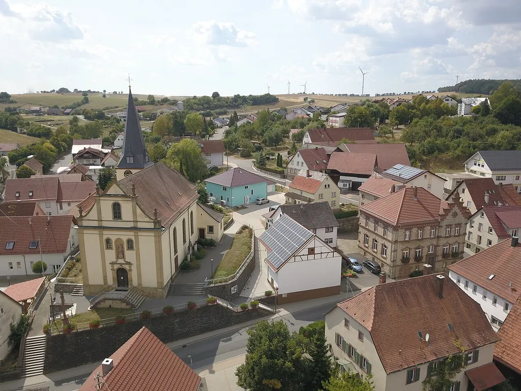 Gerichtstetten, Blick auf die Pfarrkirche St. Burkhard und das ehemalige Rathaus der Ortschaft (Buntsandsteingebäude mit Giebel, rechts im Bild), in dem bis 1966 auch die Schule untergebracht war.