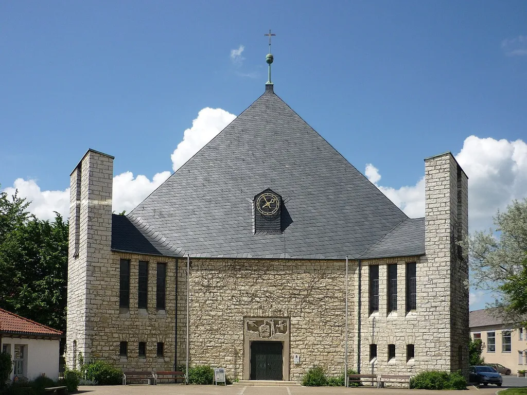 Evangelisch-lutherische Dreieinigkeitskirche; Pyramiddachbau über dreieckigem Grundriss, an den Ecken Ausluchten, mit als Glockentürme hochgeführten Stirnseiten, 1957 von Karl Pfeiffer-Haardt; mit Ausstattung; Pfarrhaus, zweigeschossiger Walmdachbau, 1960.
