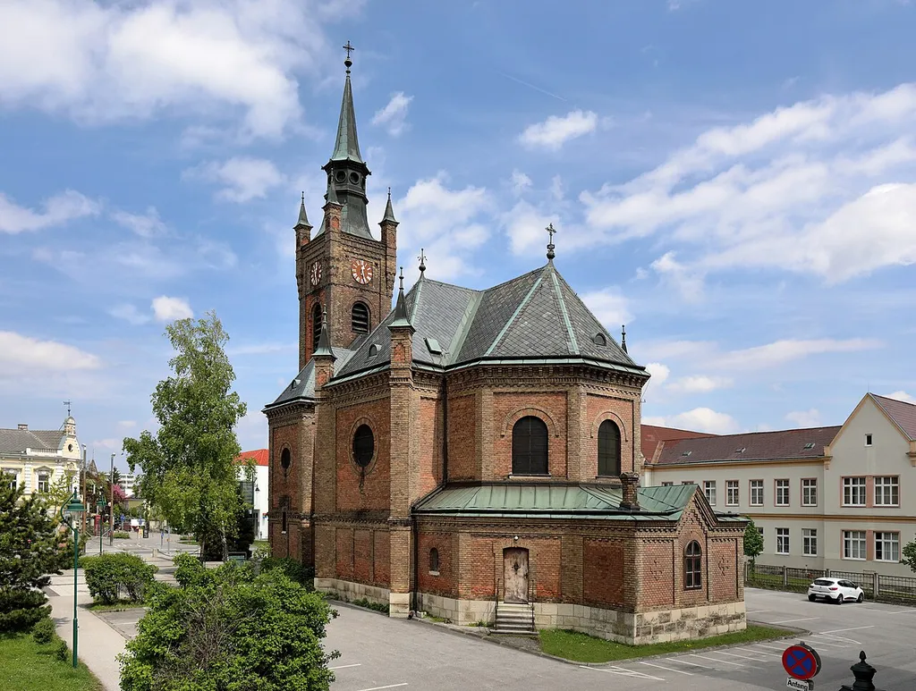 Südwestansicht der ehem. Waisenhauskirche hl. Josef in der niederösterreichischen Bezirkshauptstadt Mödling. Die späthistoristische Backsteinkirche wurde im Zuge der Errichtung des Hyrtl’schen Waisenhauses von 1886 bis 1888 nach Plänen von Sehnal gebaut.