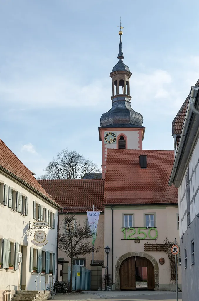 Rathausflügel, Teil der Kirchenburg, zweigeschossiger Satteldachbau mit Torbogen, 1. Hälfte 13. Jh., im 19. Jh. verändert. Zwei Wappensteine, Wappen des Fürstbischofs Julius Echter von Mespelbrunn, bez. 1606 und Ortswappen. Würzburger Straße 20, Geldersheim, Unterfranken, Bayern, Deutschland.
