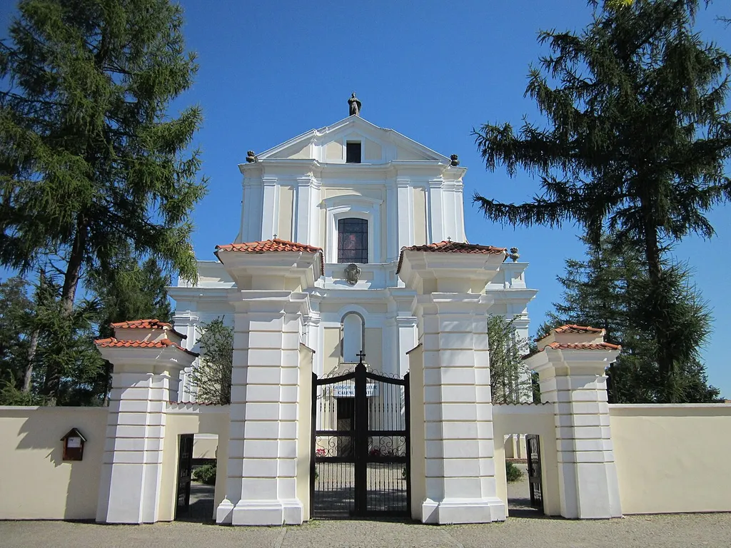 Kościół ten znajduje się przy Plac Ks. K. Kluka. Jest to barokowy kościół wzniesiony z fundacji Franciszka Maksymiliana Ossolińskiego, podskarbiego w. Koronnego, może wg. projektu arch. Mateusza Osieckiego, budowany pod kierunkiem Jana Krzysztofa Adriana Kluka (ojciec Jana Krzysztofa Kluka), staraniem syna fundatora Tomasza Ossolińskiego ukończono i konsekrowano w 1739 r. Katalog zabytków sztuki podaje datę wzniesienia na lata 1732-1737. Inne źródła daty 1737-1739, 1736-1739, 1731-1737. Pewnym jest, iż na osi fasady znajduje się kamienny portal uszakowy (rekonstruowany po 1945 r.) z datą 1737 w nadprożu, ze zwieńczeniem pokrytym płaskim reliefem ornamentu regencyjnego, ponad nim nisza; w drugiej kondygnacji wielkie okno zamknięte odcinkowo, pod nim kartusz z herbami fundatorów: Topór – Franciszka Maksymiliana Ossolińskiego i Prus III – jego drugiej żony Katarzyny z Jabłonowskich.