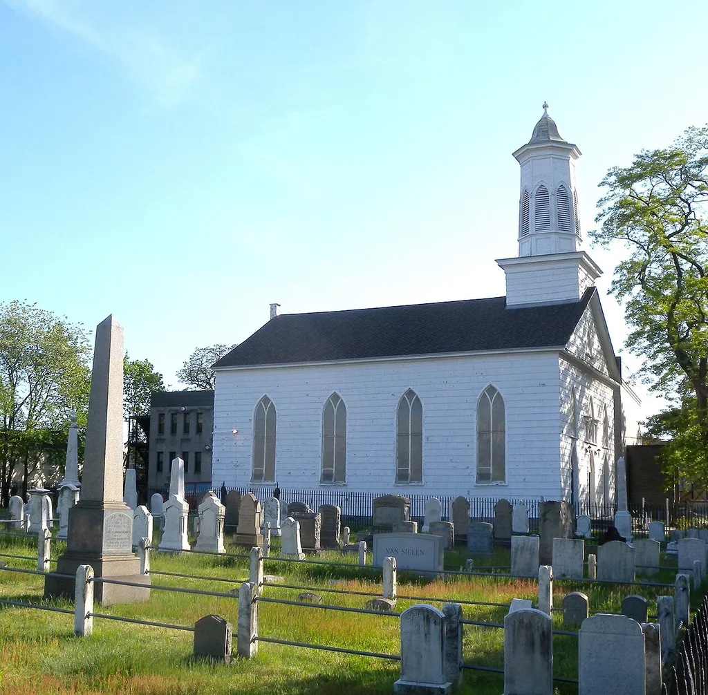 Looking southwest over the graveyard at New Lots Community Church on a sunny afternoon.