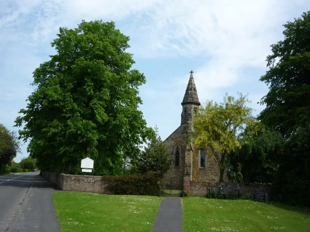 St Botolph's Church Allerthorpe, East Riding of Yorkshire, England.The road runs to meet the A1079 ahead.