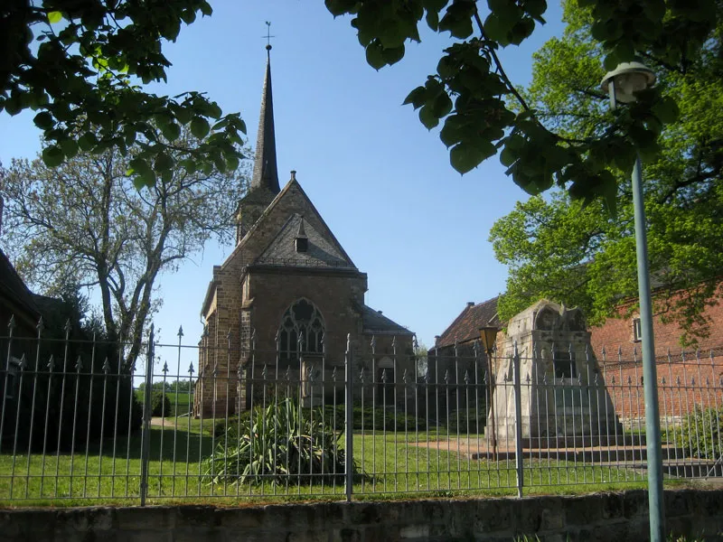Die Dorfkirche in Kriechau bei Weißenfels (einschiffiger neugotischer Bruchsteinbau mit schlankem, quadratischem Turm und Spitzhelm). Rechts davor ein Kriegerdenkmal.