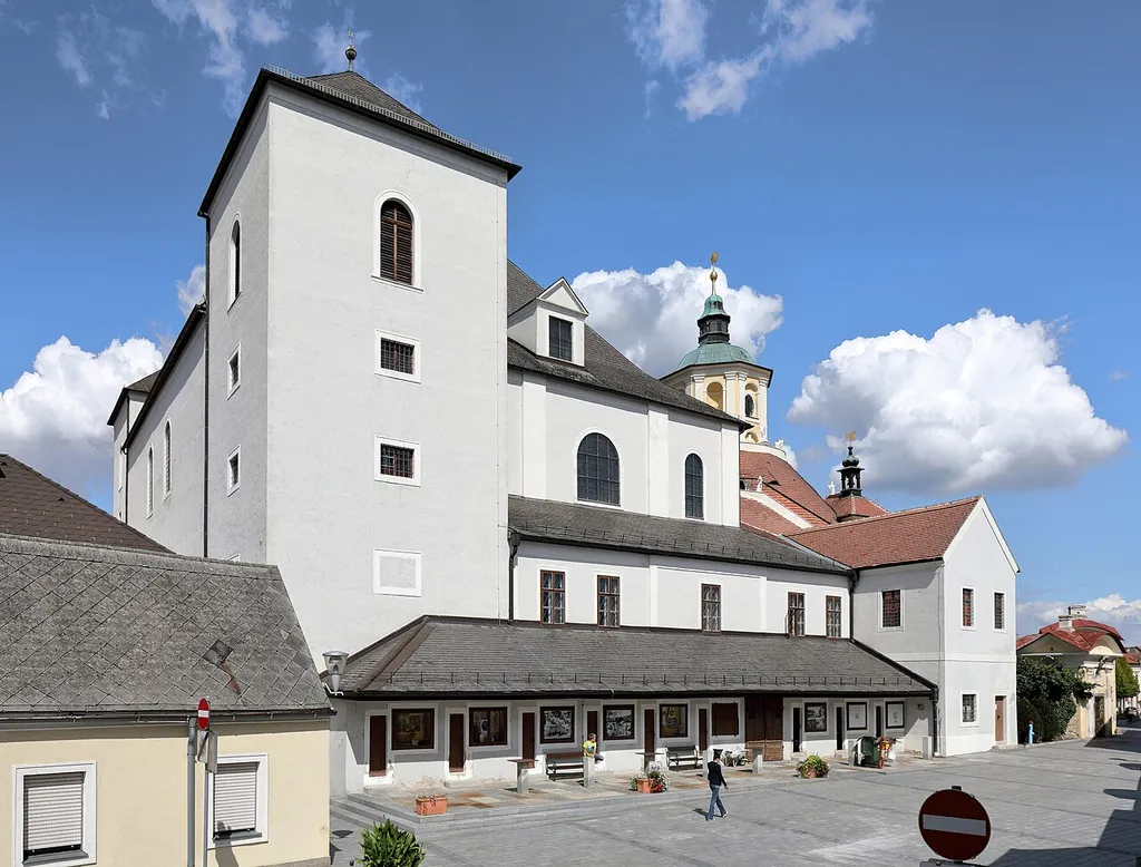 Südansicht der Haydnkirche bzw. röm.-kath. Bergkirche Mariä Heimsuchung mit ehemaligen Devotionalienläden in der burgenländischen Landeshauptstadt Eisenstadt.Die Grundsteinlegung der Kirche erfolgte 1715. Nach einer Bauunterbrechung erfolgte um 1765 die Weiterführung des Baues und 1803 die feierliche Einweihung. Der östlich angebaute Kalvarienberg wurde bereits von 1701 bis 1710 errichtet.