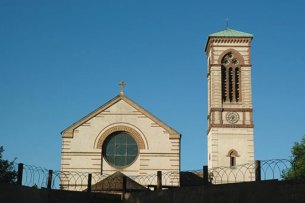 Church of England parish church of St Barnabas, Jericho, Oxford: campanile and west end of nave viewed from the west over the security fence enclosing the former boatyard.