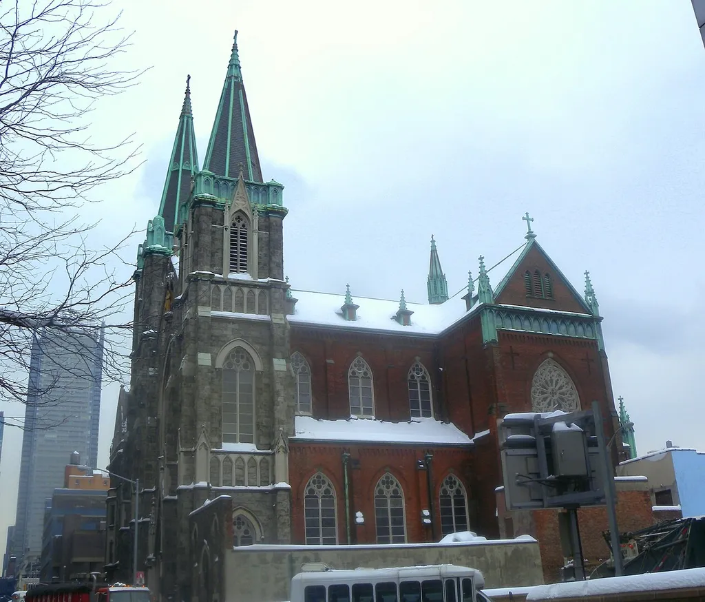 Looking east from 41st St and across Cardinal Stepanic Place at Saints Cyril, Methodius and Raphel Catholic Church on a cloudy day after snow. ZIP 10018.