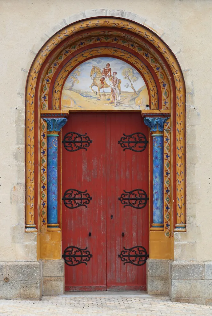 Vue du portail principal de l'église paroissiale, commune de Saint-Martin-du-Limet, Mayenne, Pays-de-la-Loire, France. Le tympan représente la scène du manteau.