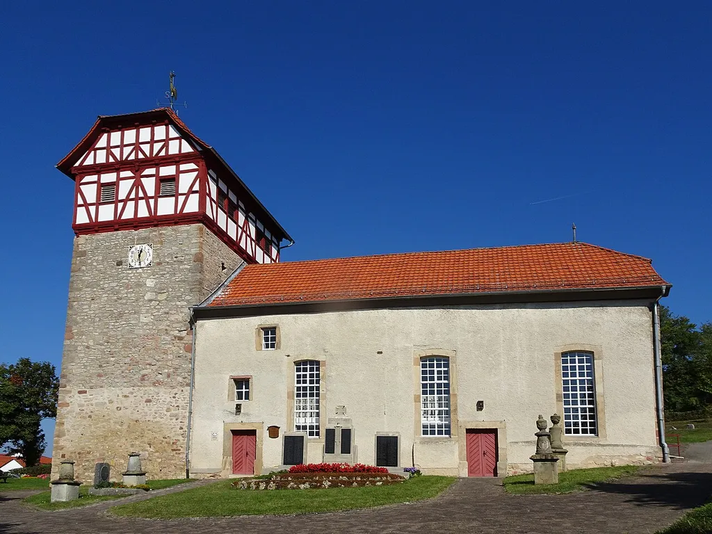 Die evangelische Kirche in Ulfen. Ulfen ist ein Stadtteil von Sontra im nordhessischen Werra-Meißner-Kreis. "Die ursprünglich als Wehrkirche angelegte Anlage prägt entscheidend die Ortssilhouette Ulfens. Dem im Jahr 1363 errichteten Westturm wurde 1705 ein Glockengeschoß in markanter Fachwerkkonfiguration aufgesetzt, das den Ort schon von weitem ankündigt. Das gedrungene Schiff wurde etwa zeitgleich mit dem Turm errichtet und schließlich im Jahr 1790 soweit erhöht, dass der First des Langhausdaches dicht unter dem Glockengeschoß endet. Darüber hinaus wurde die Längenausdehnung des Schiffes verdoppelt, um ausreichend Platz für die Besucher des Gottesdienstes zu schaffen." Text aus: Denkmaltopographie Bundesrepublik Deutschland, Kulturdenkmäler in Hessen. Werra-Meißner-Kreis I, Altkreis Eschwege. Peer Zietz, Thomas Wiegand, Braunschweig: Vieweg Verlag, 1991, ISBN 3-528-06240-1.