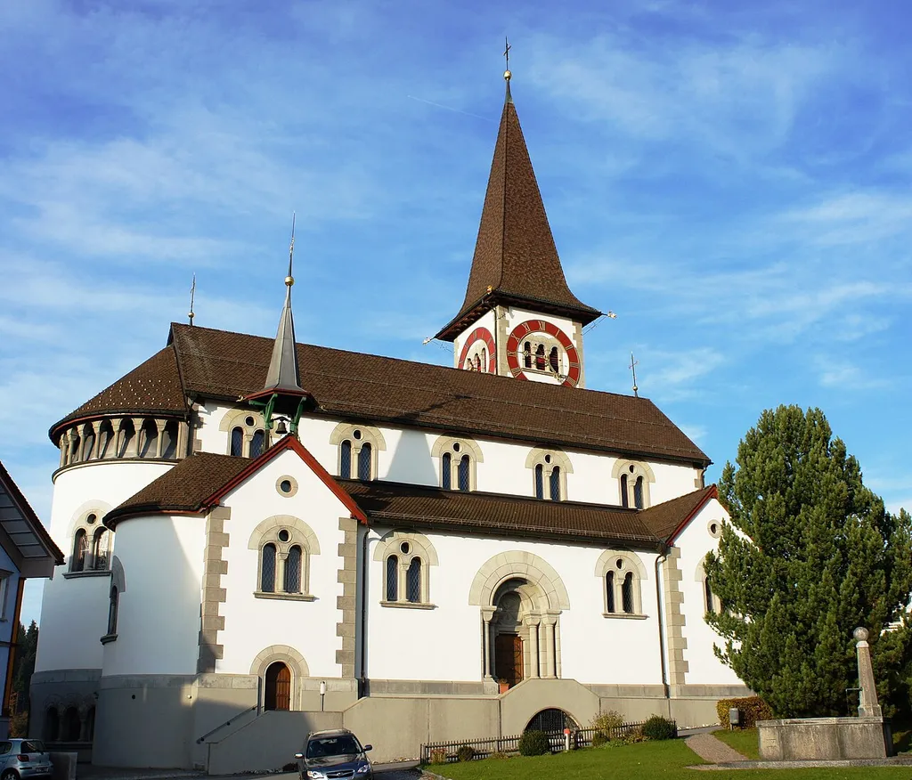 Blick aus Südwesten auf die Kirche in Haslen. Im Vordergrund der Dorfplatz mit kleinem Park und Brunnen.