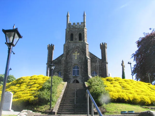 Holy Cross Killishen This Church is located on a small hill, just of the road. A beautifully kept Church with steep steps to its front door, well worth the climb, both for the view and the fantastic array of shrubs on the ascent.