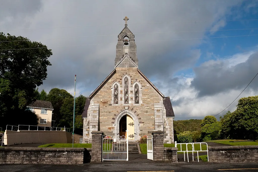 West façade of the Church of the Sacred Heart in Glengarriff at the N71, erected in 1902. The belfry tower and the window trimmings were set in limestone supplied by Hickey and sons, Aherla. The other stones came from Carraig an Mhada, a local quarry. The bell was crafted by Byrne of Dublin.