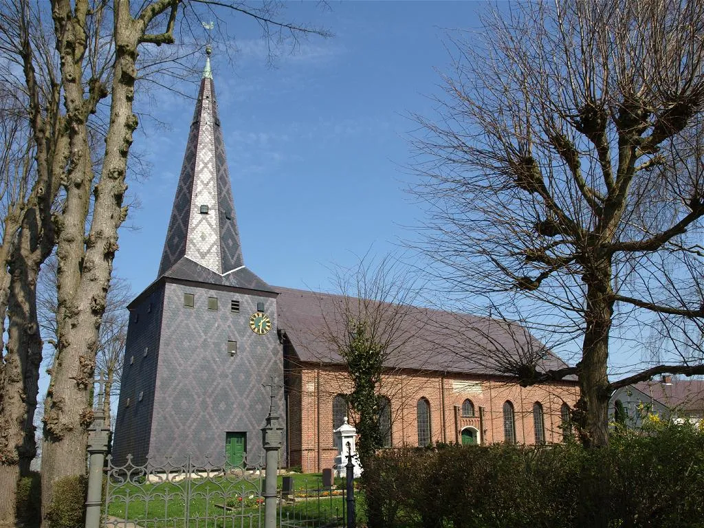Kollmar (Schleswig-Holstein, Germany), church (built in 15th century) , photo 2009 - The Church is a single-nave brick building with a three-sided east end. It was built on the old dike line in the middle of the 15th century. The interior was renewed in the 17th century, and the exterior was redesigned in 1858. - The wooden west tower probably dates from the 17th century. It is completely covered with slate. Different colored slates are arranged in a diamond pattern.
