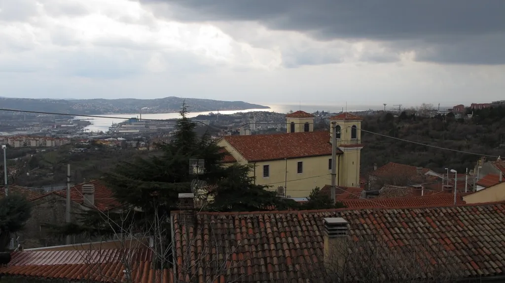 In primo piano la chiesa di San Giuseppe della Chiusa, sullo sfondo la baia di Muggia.