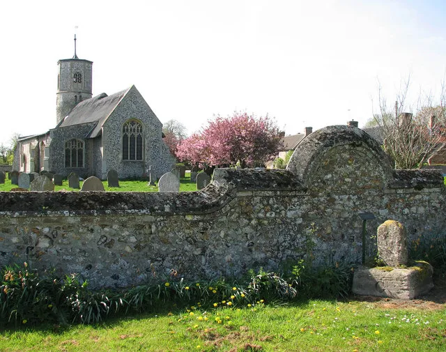 St Mary's church The remains of a medieval stone cross can be seen in foreground (right). Many prehistoric tools, Saxon jewellery and Roman coins have been unearthed in the area and there are also the remains of two medieval crosses bearing witness to regular markets having taken place on the village green and at the crossroads. St Mary's church > https://www.geograph.org.uk/photo/1269098 - https://www.geograph.org.uk/photo/1269159 - https://www.geograph.org.uk/photo/1269163 is located at the end of the large village green. It has a thatched roof and its round tower > https://www.geograph.org.uk/photo/1269095 dates from the early 11the century and is believed to be one of the earliest in Norfolk which is topped by an early 15th century octagonal bell stage. Inside, the bell window is off-centre. The interior was restored during Victorian times but two old brasses have survived. The pulpit > https://www.geograph.org.uk/photo/1269184 is Jacobean. There is also an interesting altar chest > https://www.geograph.org.uk/photo/1269173 in the south aisle which was made by J. Bramah &amp; Son, London, and is dated to 1835. The perhaps most interesting feature contained in this church are two pieces of graffiti (protected behind perspex) believed to have been made by a mason on blocks of stone which around 1340 were built into the south wall so that the south aisle > https://www.geograph.org.uk/photo/1269165 could be added. The depiction of a devil > https://www.geograph.org.uk/photo/1269196 is described by archaeologists as among the best in the country. For more information see http://www.norfolkchurches.co.uk/beachamwellmary/beachamwellmary.htm