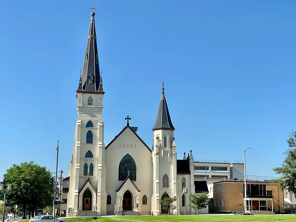 Built in 1888 as the First Christian Church, this Gothic Revival-style building was sold to the Roman Catholic Diocese of Lincoln in 1904 to serve as a cathedral, and underwent significant renovations and suffered a major fire in 1906, with the renovations to building being completed in 1908. The building features a painted brick exterior, a gabled roof, two towers of varying heights with octagonal spires, gothic arched bays, stained glass windows, buttresses, recessed entrance portals, pinnacles, brick corbeling, and a rough-hewn stone base. The building today serves as St. Mary’s Catholic Church, as a new cathedral was constructed in southwest Lincoln during the mid-20th Century.