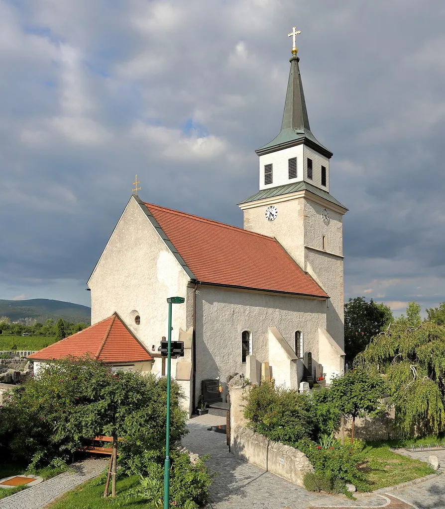 Südwestansicht der röm.-kath. Pfarrkirche hl. Anna in der niederösterreichischen Marktgemeinde Sooß.Die spätgotische Chorturmkirche wurde im 15. Jahrhundert errichtet und zur Barockzeit verändert. Sie befindet sich im Norden des Ortes auf freiem Feld, inmitten des ummauerten, im Norden, Osten und Westen von einem Graben umgebenen Friedhofs.