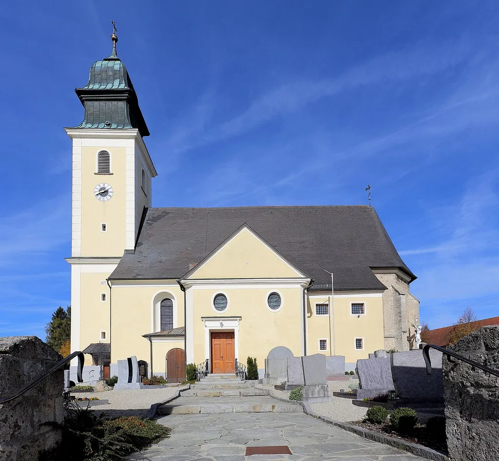 Südansicht der katholischen Pfarrkirche Mariä Himmelfahrt der oberösterreichischen Gemeinde Weilbach. Ein Tuffsteinbau dessen Langhaus spätbarock ist (1775). Diesem Gegenüber befindet sich ein leicht eingezogener zweijochiger, gotischer Chor mit 5/8-Schluss. Der barocke Westturm mit einer hohen Haube wurde um 1780 errichtet.