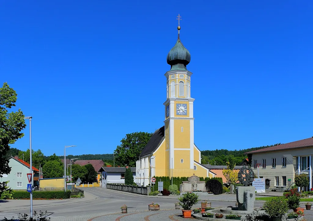 Westansicht des Dorfplatzes mit der katholischen Pfarrkirche hl. Jakob der oberösterreichischen Gemeinde Schalchen.