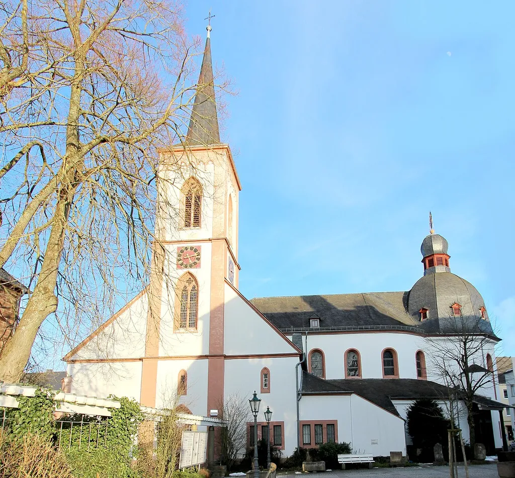 54634 Bitburg, Rathausplatz. Im Kern spätgotischer Saal, Erweiterung zu dreischiffiger Halle mit Westturm 1860, Architekt Alexander Franz Himpler, lotrechte, barockisierende Erweiterung, 1922/23, Architekt Eduard Endler, Köln; im Winkel zwischen Alt- und Erweiterungsbau Barockportal, 1751; mit Ausstattung. Orgelbau der Firma Späth 1962; später (1986) von Gustav Cartellieri aus Wittlich überarbeitet. Aufnahme von 2018.