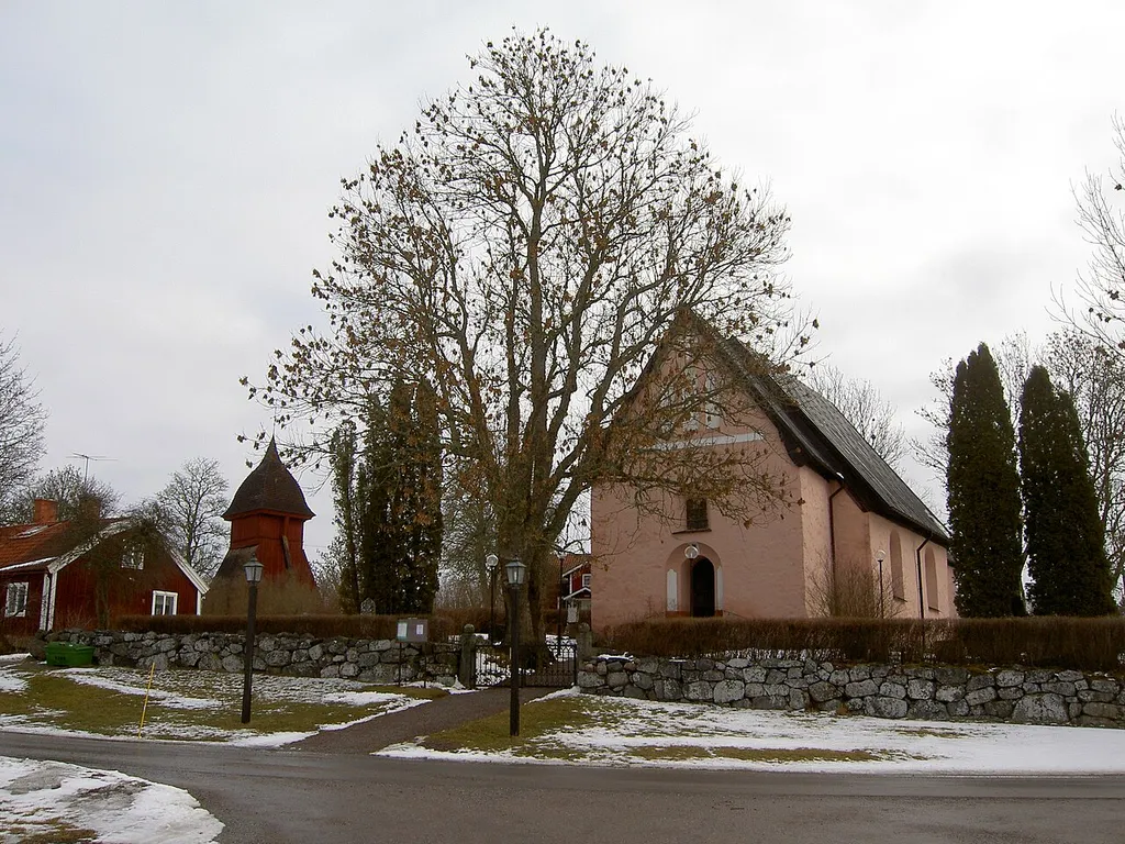Haga kyrka från parkeringsplatsen. Kyrkobyggnad och klockstapel är synliga.