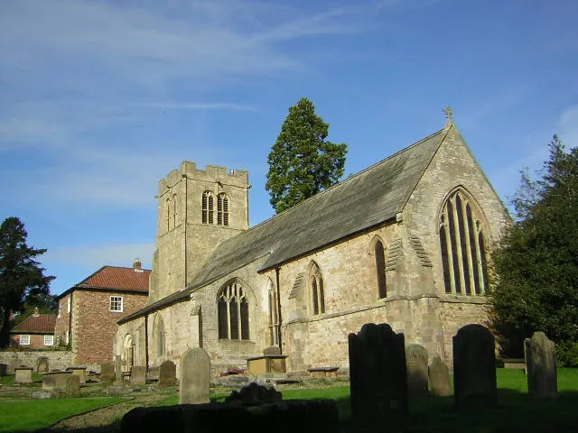 Goldsborough St Mary's Church seen from the circular base of an old tombstone that looks like it had an upright at some time but is now severely eroded.