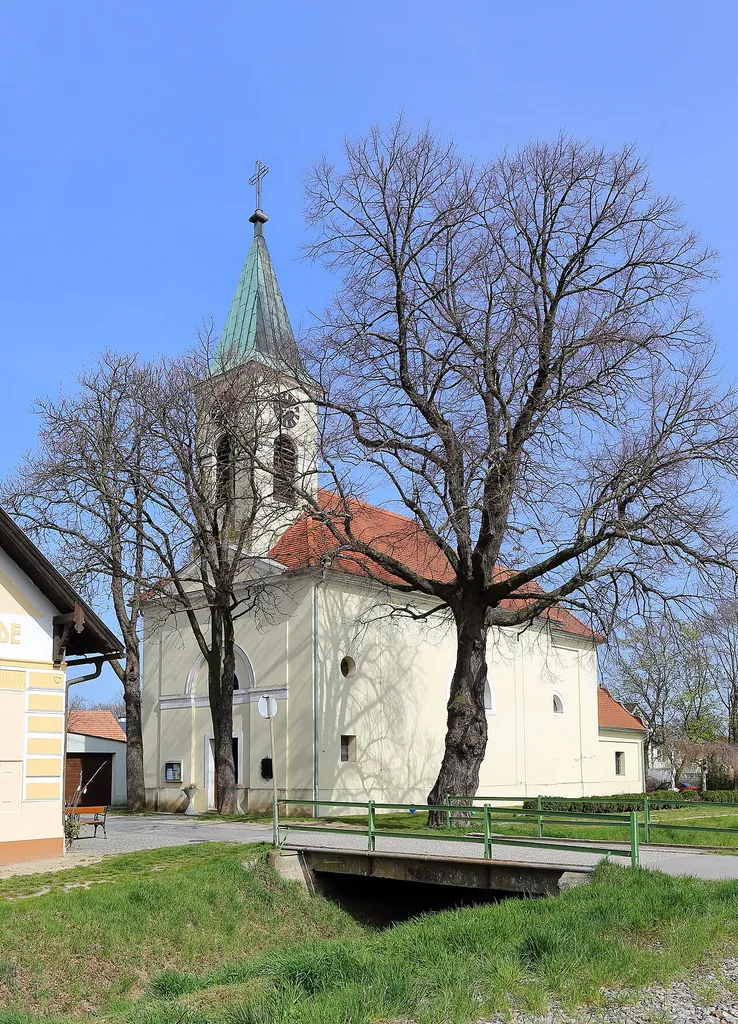 Südwestansicht der römisch-katholischen Filialkirche hl. Johannes Nepomuk in Ketzelsdorf, ein Ortsteil der niederösterreichischen Stadt Poysdorf. Der Chor und die Sakristei wurden im 4. Viertel des 18. Jahrhunderts errichtet und das Langhaus sowie die Turmfassade 1838.